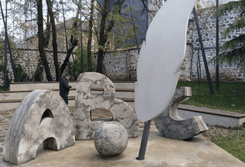 Giant stone letters and feather monument to the first Albanian school in Korca, Albania