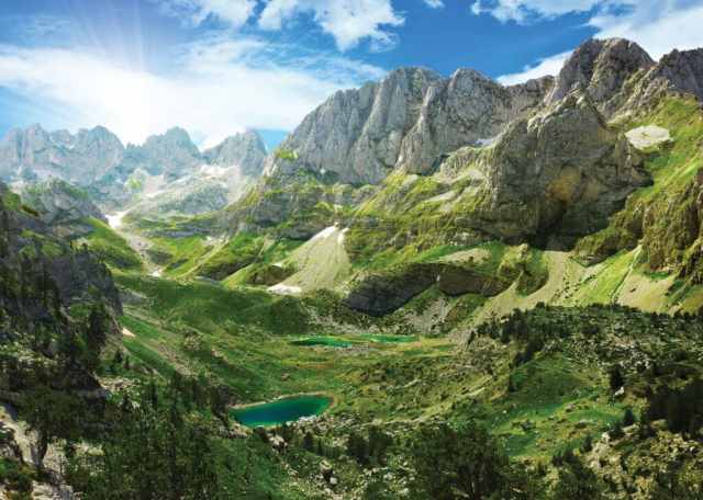 Green valley and alpine lake below the peaks of the Albanian Alps between Theth and Valbona