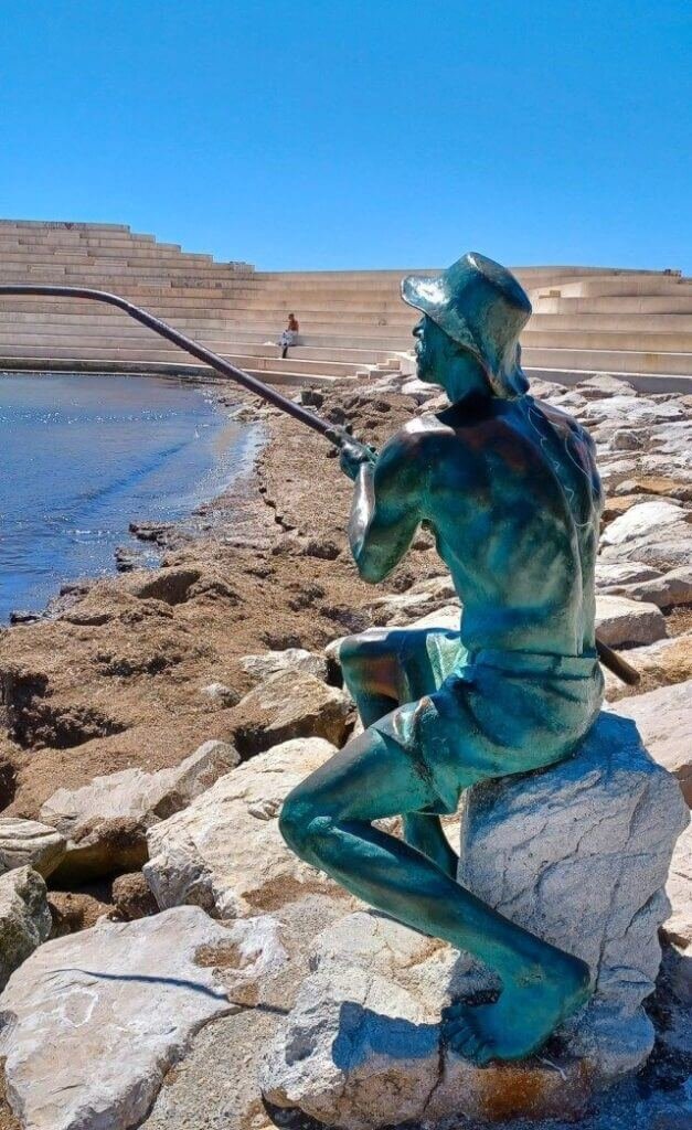 Bronze fisherman statue by water