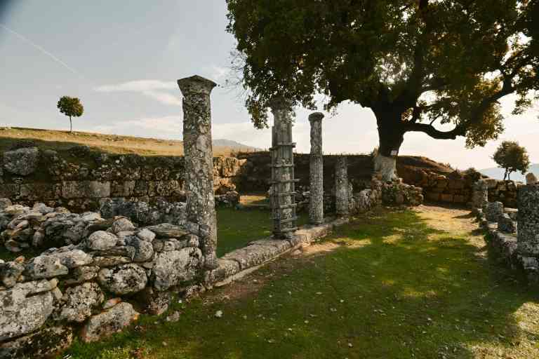 Ancient stone columns and ruins of the Antigonea Archaeological Park under a tree, near Gjirokastra in southern Albania