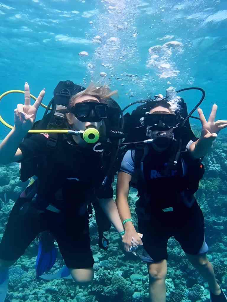 Two scuba divers giving hand signals underwater during a dive in Albania
