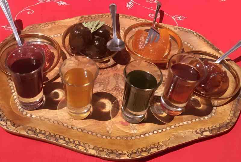 A carved tray with small glasses of different raki at a tasting in Berat