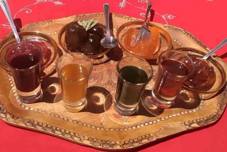 A carved tray with small glasses of different raki at a tasting in Berat