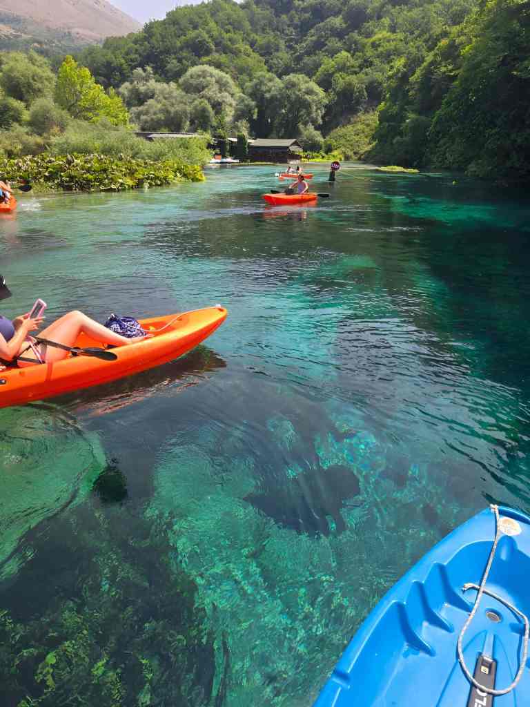 A person kayaking on the crystal-clear turquoise water of the Blue Eye near Saranda