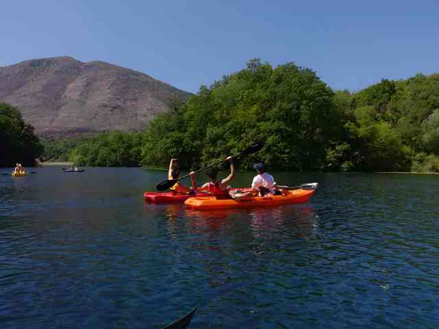 A couple kayaking on clear water with mountains behind near Saranda