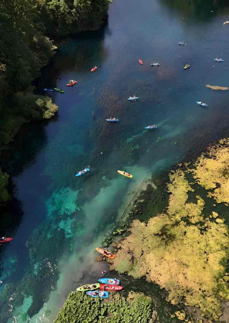 Many kayakers on the clear turquoise water of the Blue Eye near Saranda
