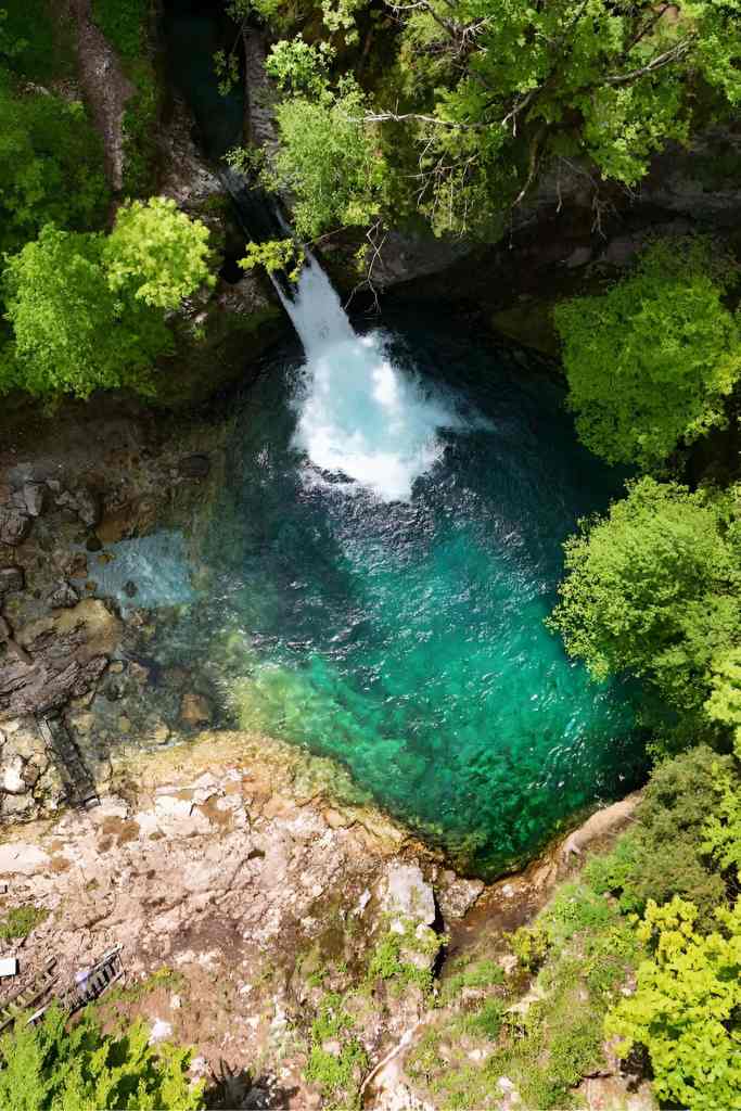The turquoise pool and small waterfall of the Blue Eye of Theth in the Albanian Alps on a Theth day trip from Tirana