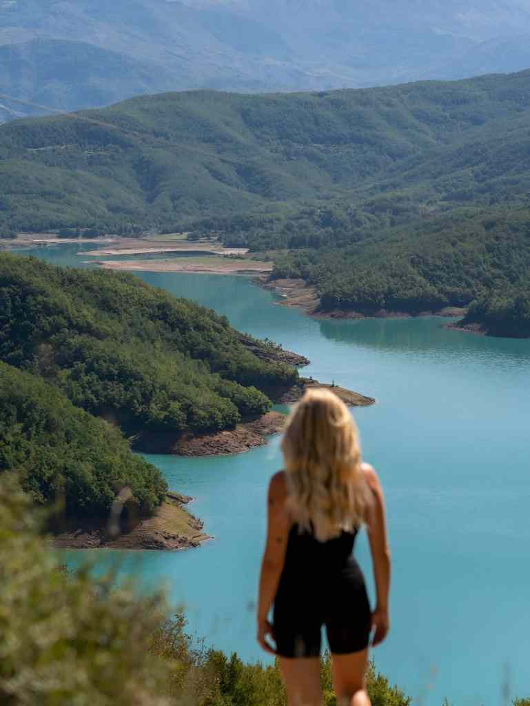 A hiker looking out over the turquoise Bovilla Lake and forested mountains near Tirana