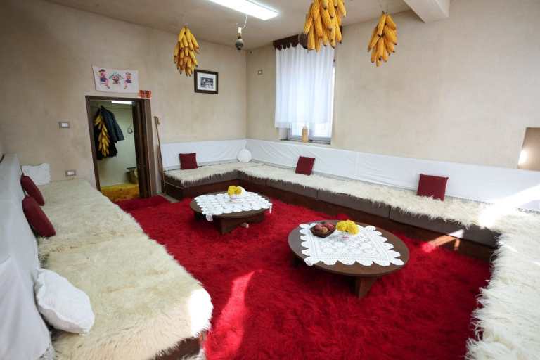 A traditional room with red carpets set for a cheese tasting in Lazarat