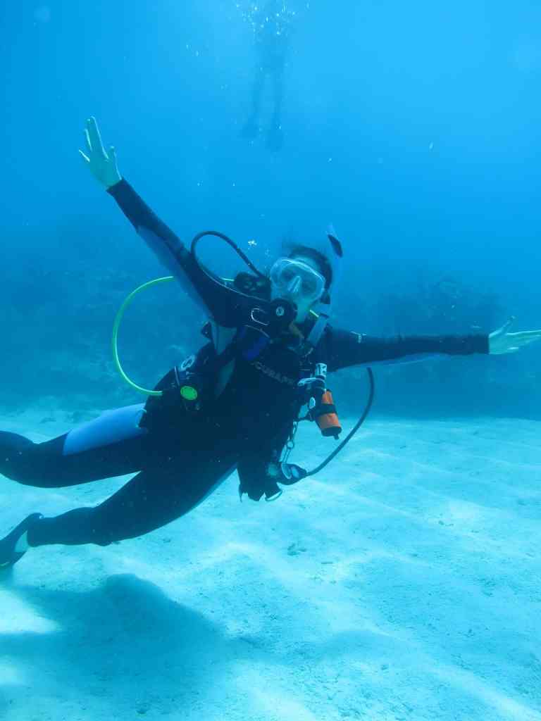 Scuba diver gliding over a sandy seabed in clear blue water on the Albanian Riviera