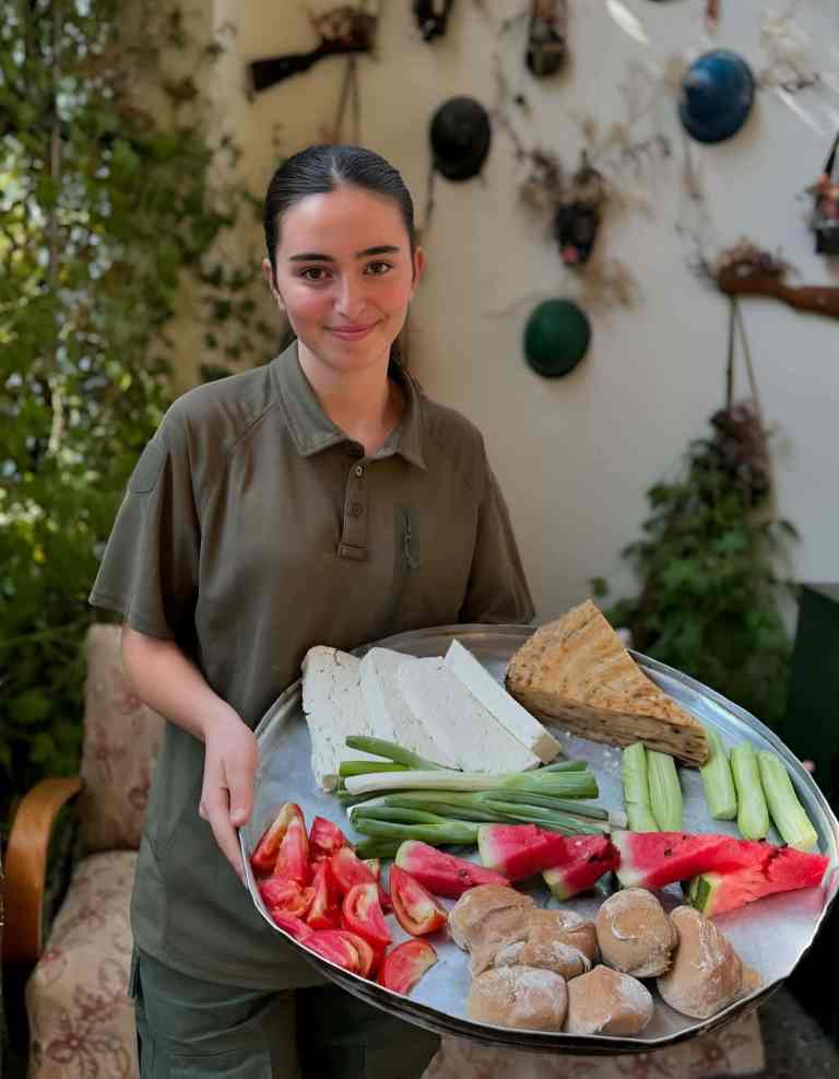 Host holding a platter of fresh vegetables and food at a farm-to-table lunch near Tirana