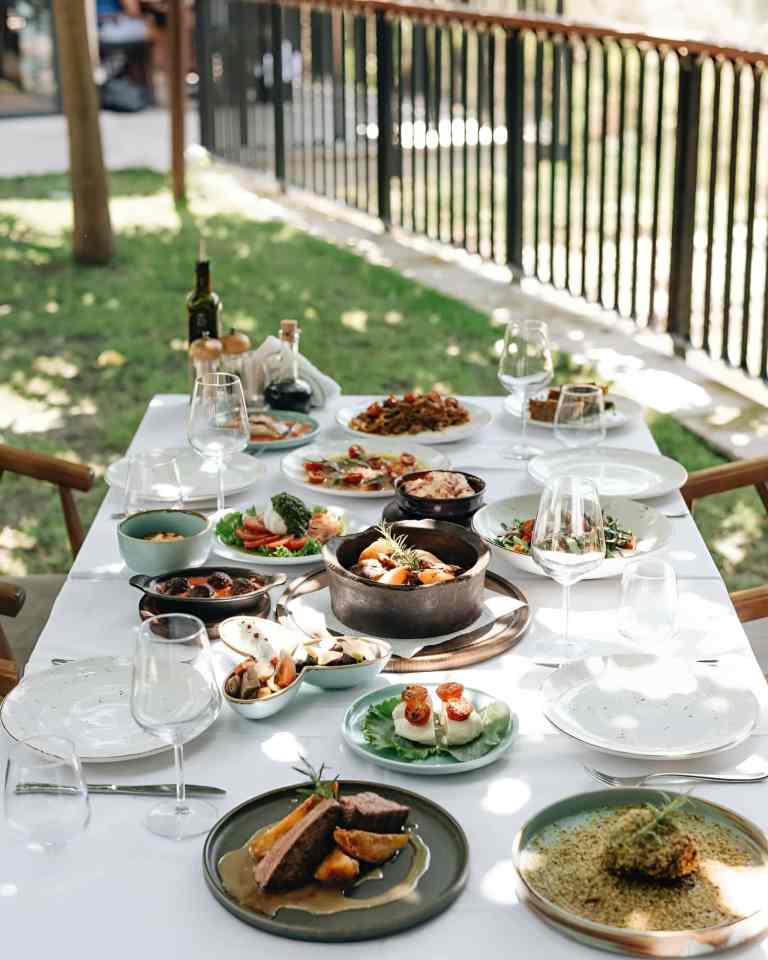 Outdoor table set with wine and a full lunch on a deck at a winery near Tirana