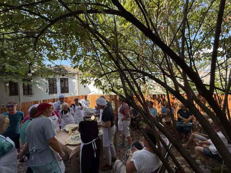 A large group cooking and dining under trees at a Gjirokastra class