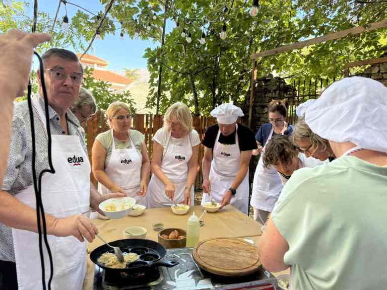 A host showing a group how to cook at a Gjirokastra cooking class