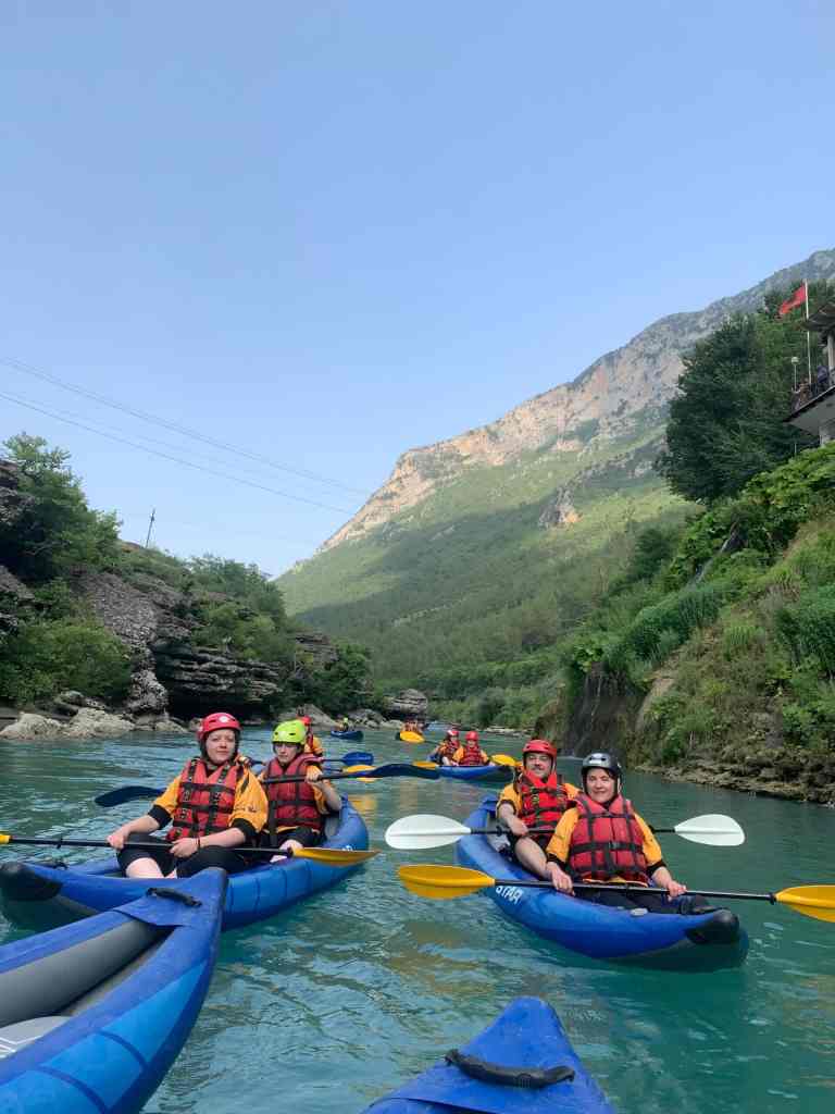 A group of kayakers paddling toward the camera on the Vjosa near Përmet