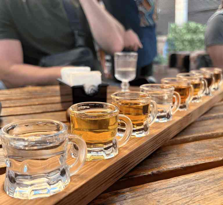 A row of raki glasses on a wooden board for a tasting in Korca