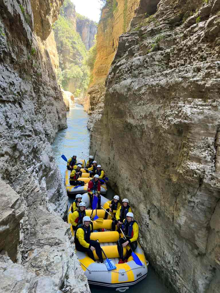 A raft going through a narrow part of the Osum Canyon with high limestone walls