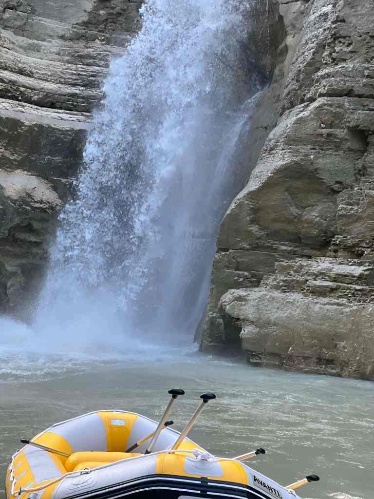 Rafters in a raft at the base of a waterfall in the Osum Canyon