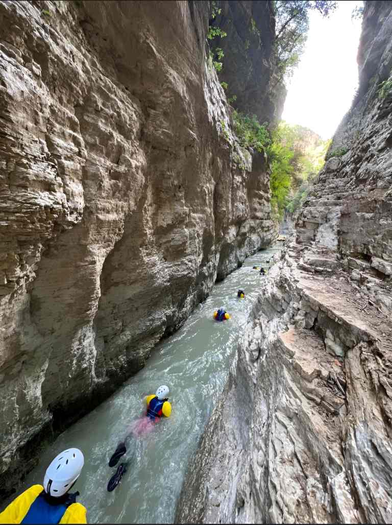 People in helmets and life jackets floating through the narrow Osum Canyon on the river in Albania