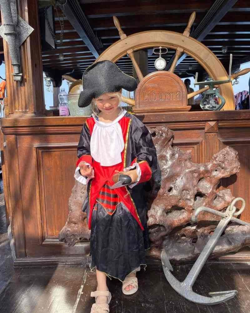 A guide dressed as a pirate standing on the deck of the wooden tour boat during a Vlora boat tour along the Ionian coast