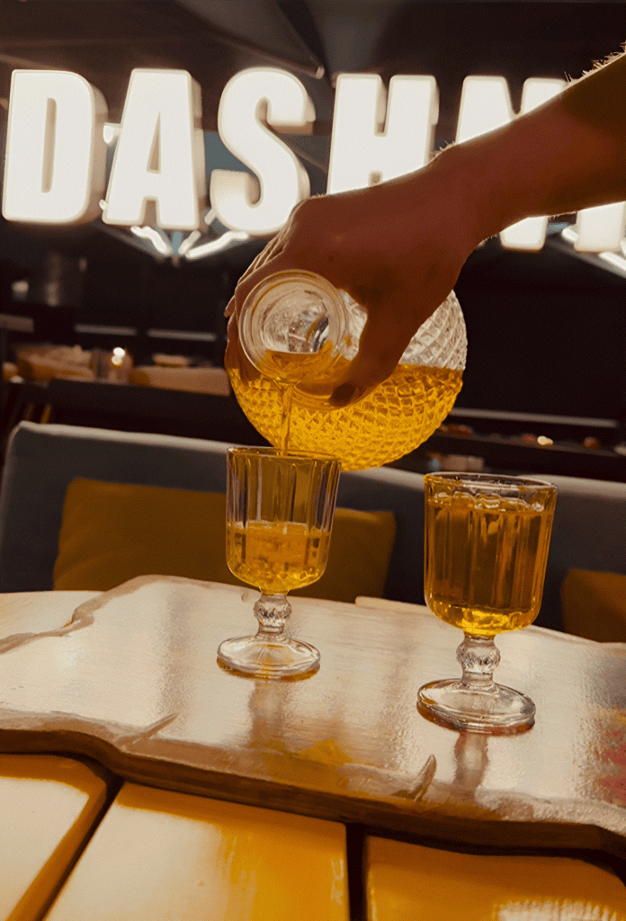 A host pouring raki into glasses at a bar in Tirana