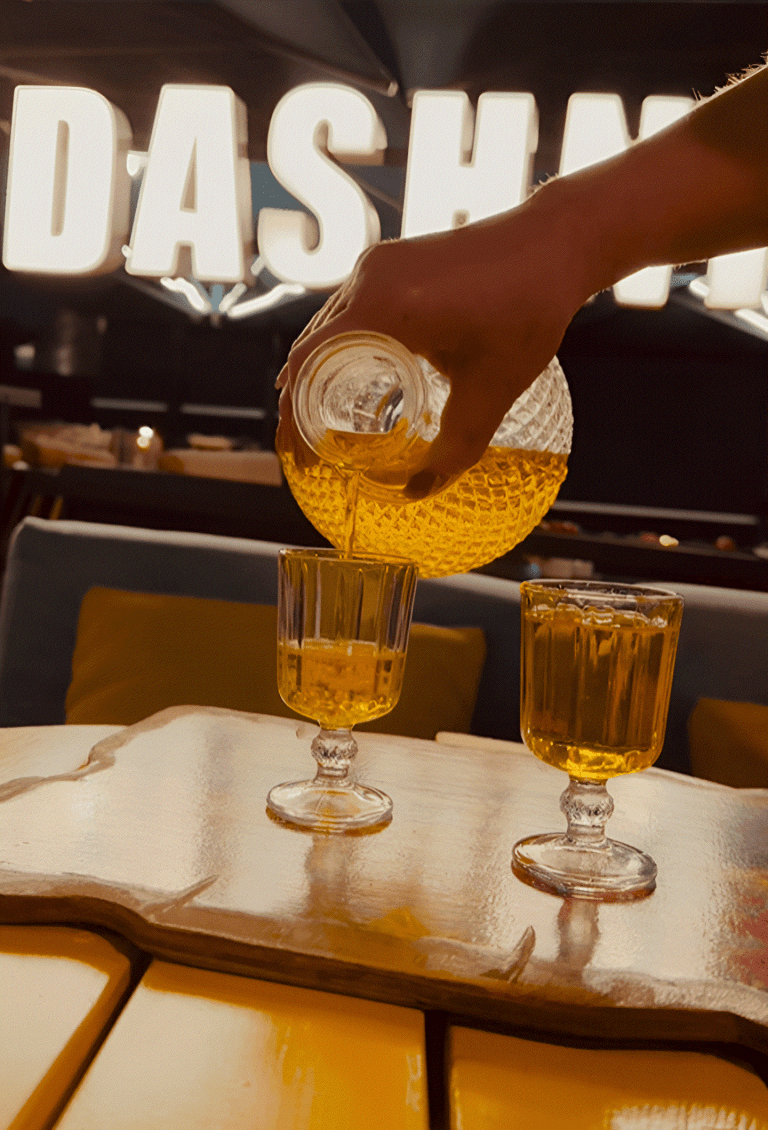 A host pouring raki into glasses at a bar in Tirana