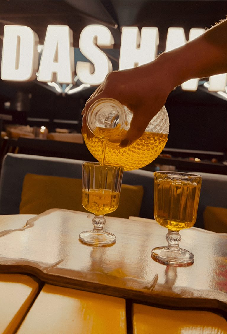 A host pouring raki into glasses at a bar in Tirana
