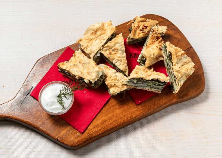 Raki served with byrek and meze on a wooden board in Tirana