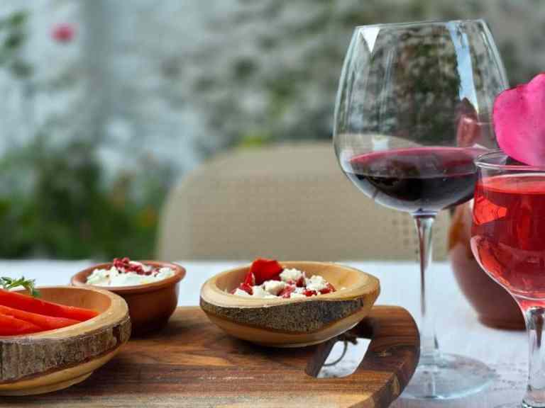 Glass of red wine beside wooden boards of food at a Shkodra food tasting