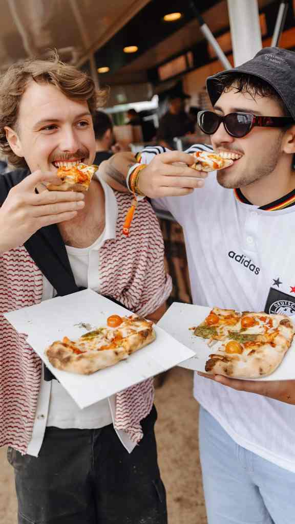 Two people eating street food slices on a food tour in central Tirana