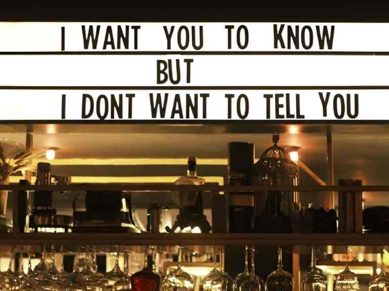 Cocktail bar in Blloku, Tirana with bottles and a lit letter-board sign during a pub crawl