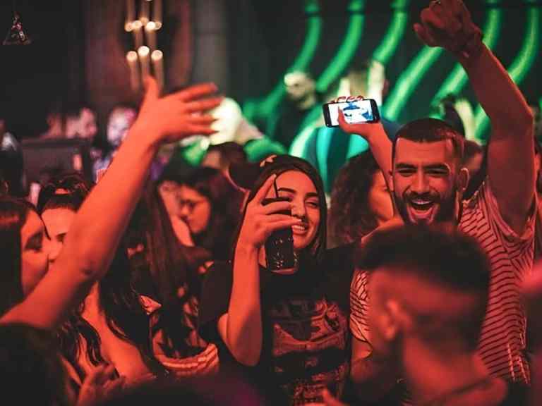 Crowd enjoying nightlife with colored lights at a club in Tirana