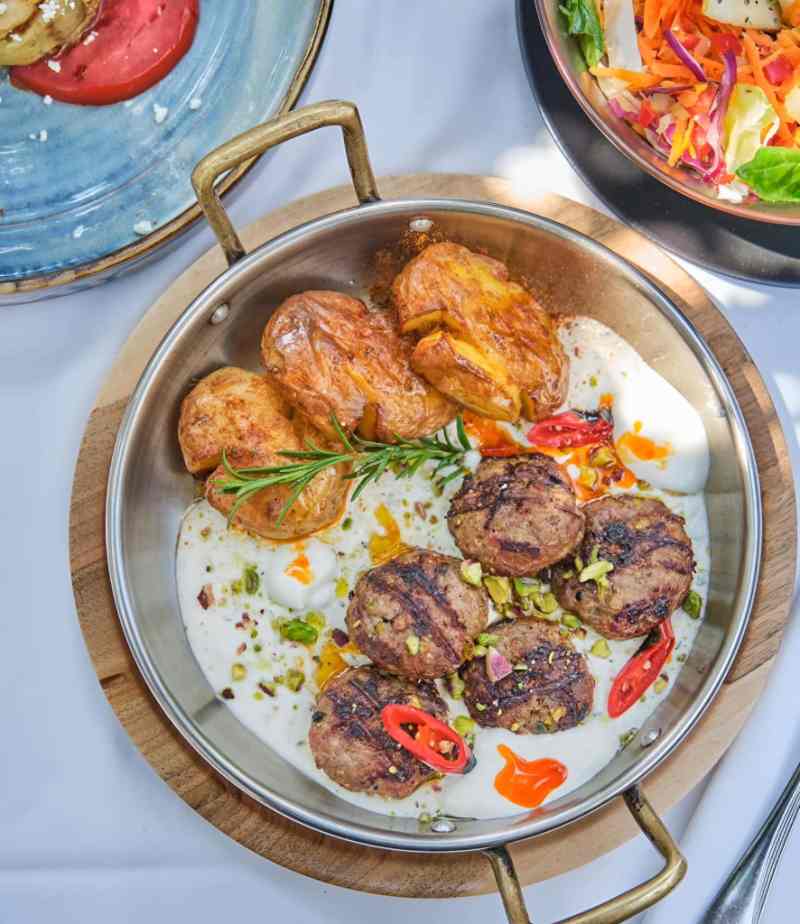 Pan of traditional Albanian dishes including fergese and meatballs in Tirana
