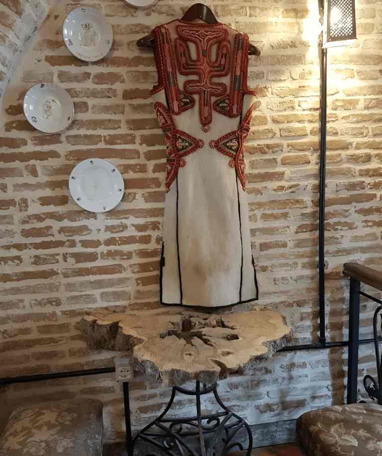 A traditional Korca costume on the stone wall of a tavern