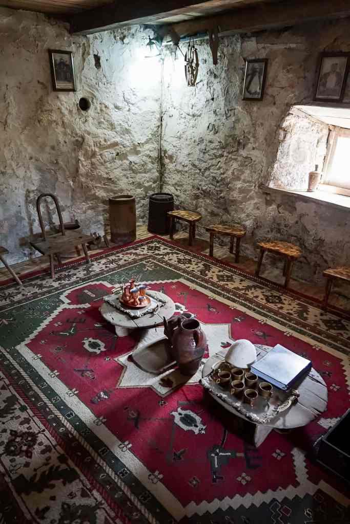 The interior of a traditional Theth stone guesthouse with carpets and a local meal in the Albanian Alps