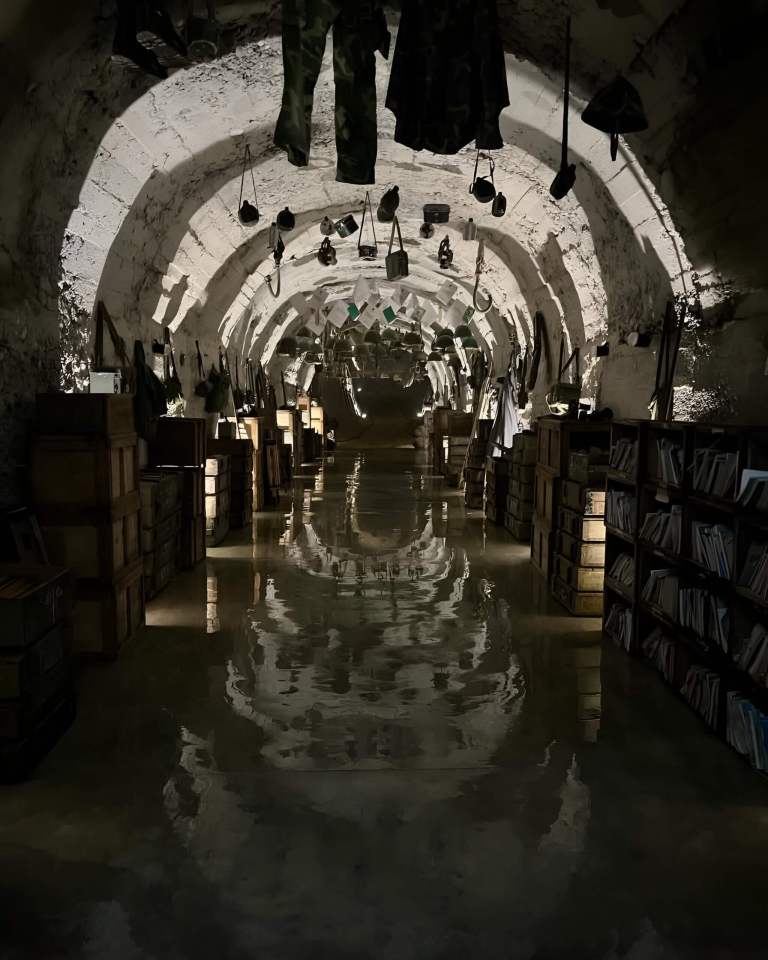 Underground military tunnel lit with lights and lined with displays at an ex-military base in Albania