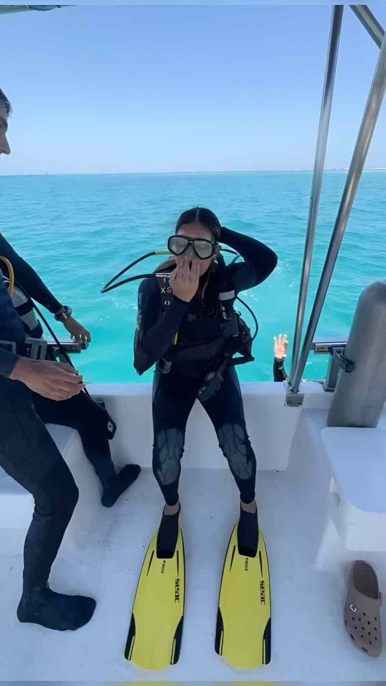Diver in a wetsuit putting on yellow fins on a dive boat before scuba diving in Albania