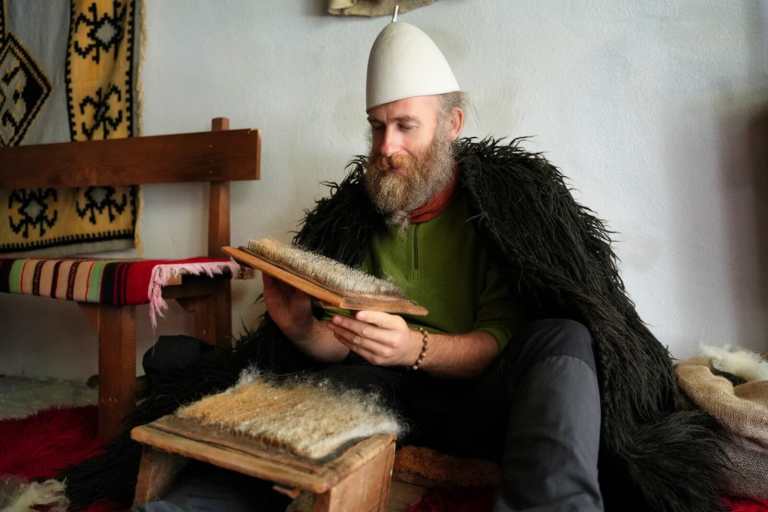 A local host in traditional Albanian dress holding wool in Lazarat