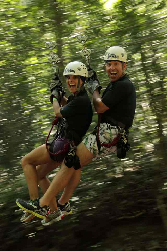Two people ziplining together over the forest in Theth