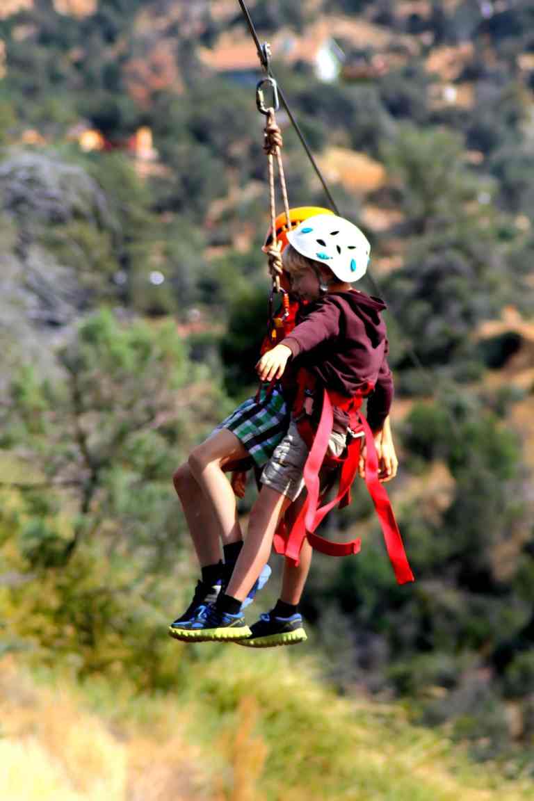 Child ziplining over a green hillside in Theth, family friendly