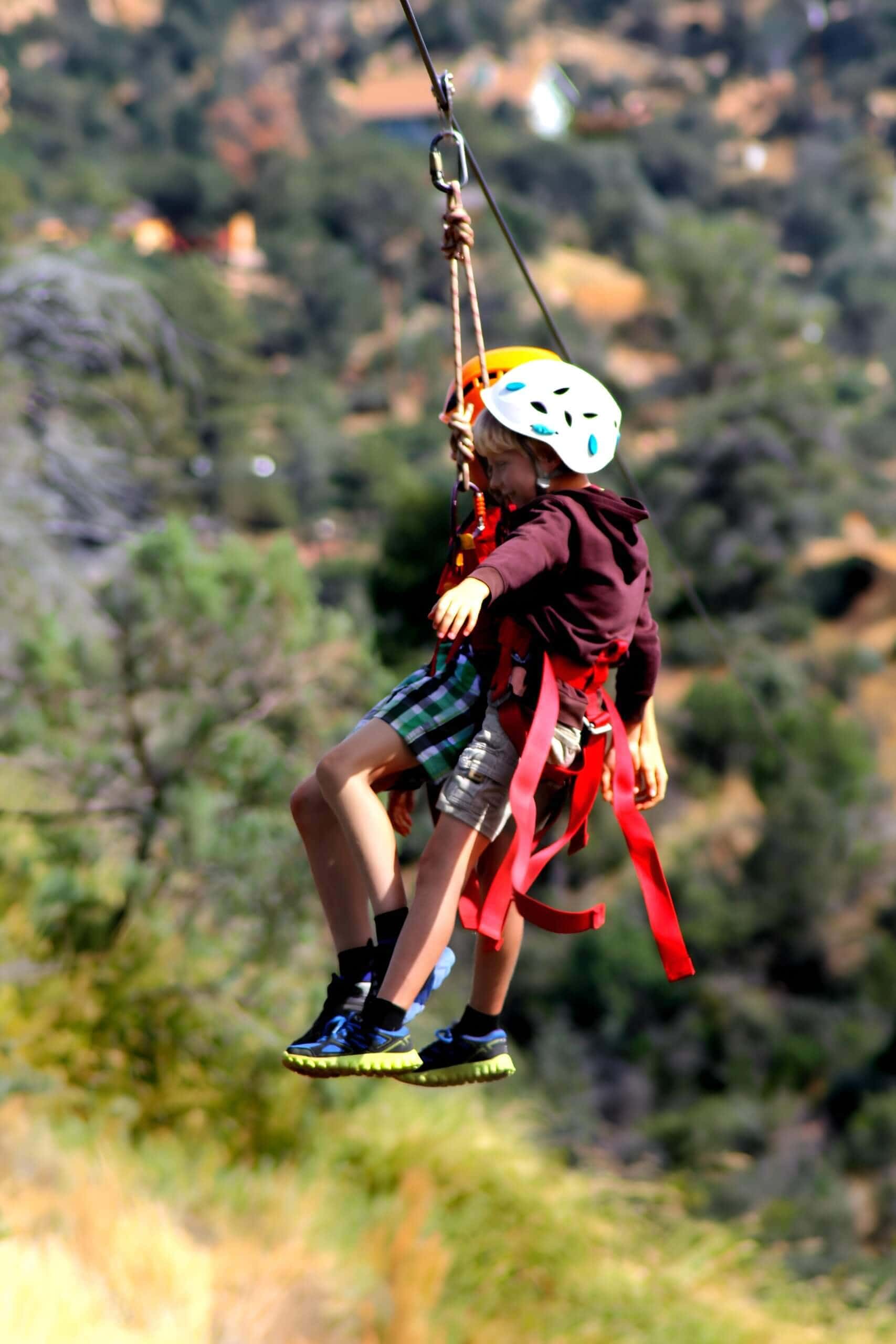 Child ziplining over a green hillside in Theth, family friendly