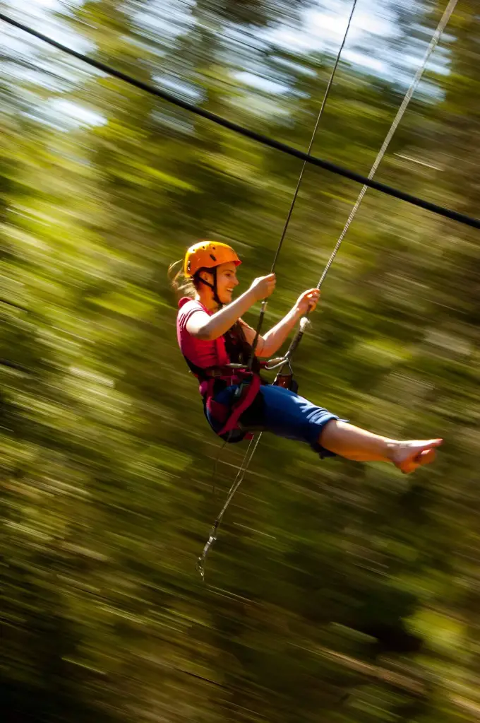 Person speeding along the zipline through the Theth forest
