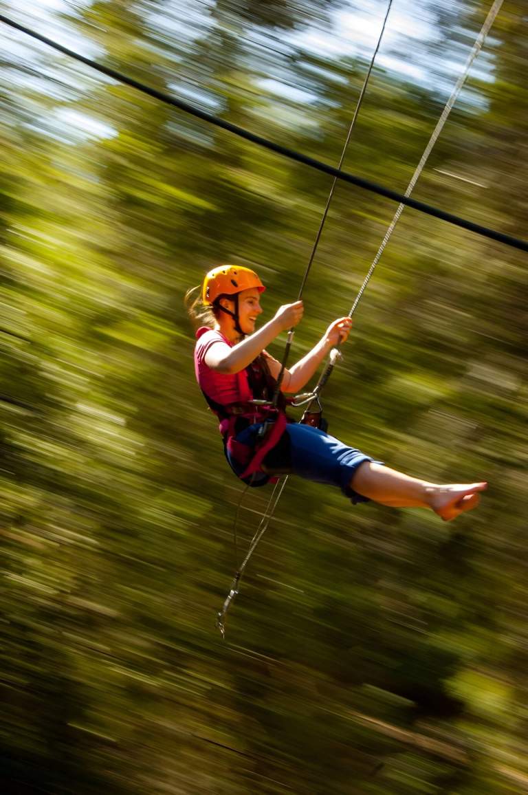 Person speeding along the zipline through the Theth forest