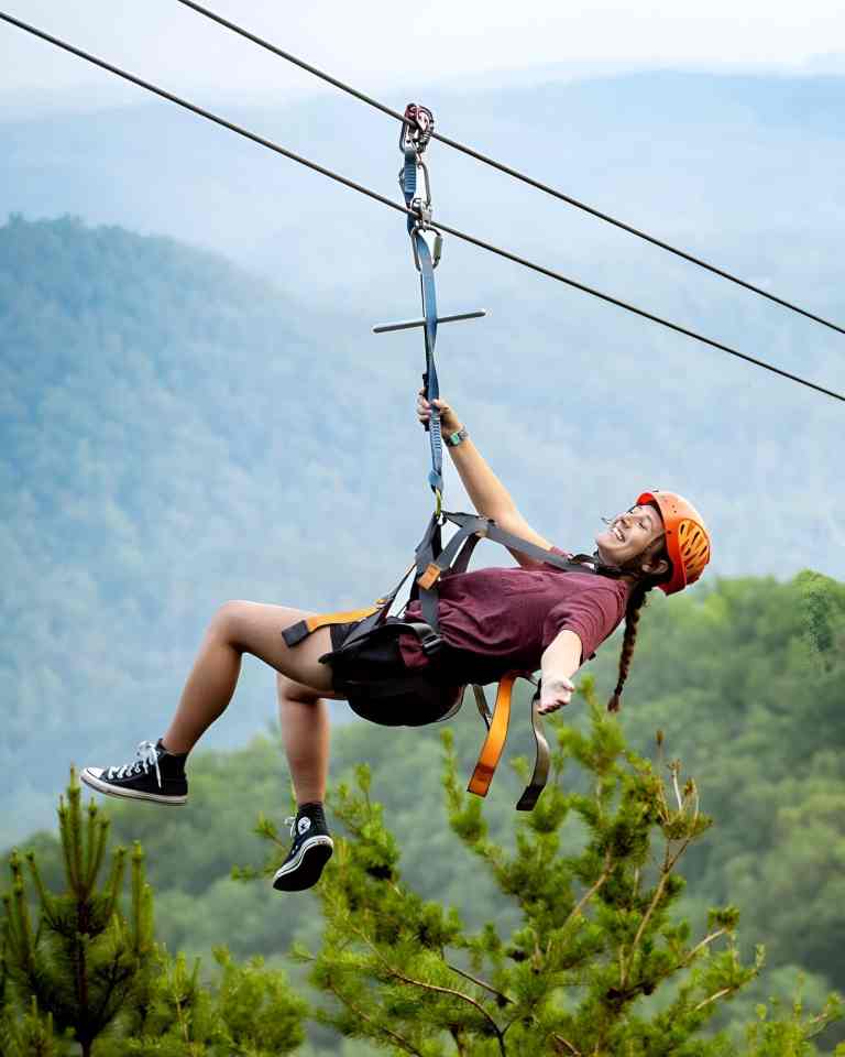 Woman ziplining over green hills near Tirana