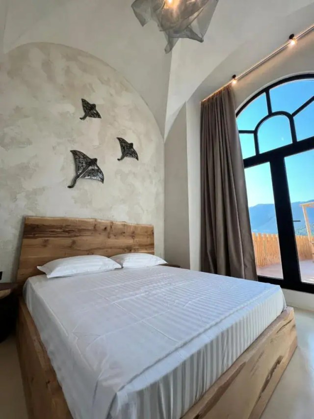 Boutique room with vaulted stone wall, live-edge wood bed and mountain-view window, Albania
