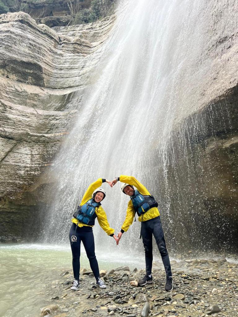 Two rafters in yellow jackets under a waterfall in Osum Canyon near Berat, the rafting day of an Albania adventure tour
