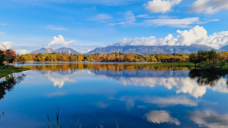 Calm lake reflecting mountains and autumn trees near Tirana, Albania