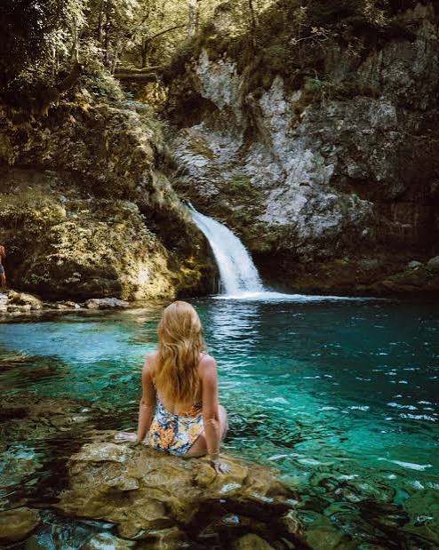 A woman sitting on a rock at the turquoise Blue Eye spring in southern Albania