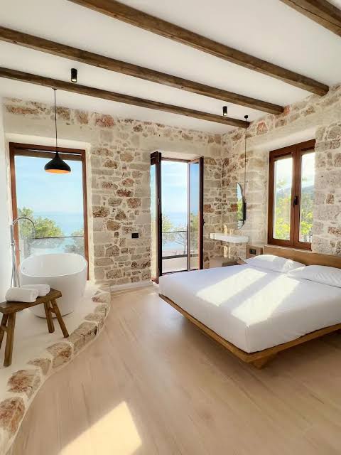 A stone-walled boutique hotel room in Albania with a freestanding bath and sea view