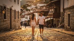 A couple walking hand in hand through the cobbled old town of Berat at golden hour